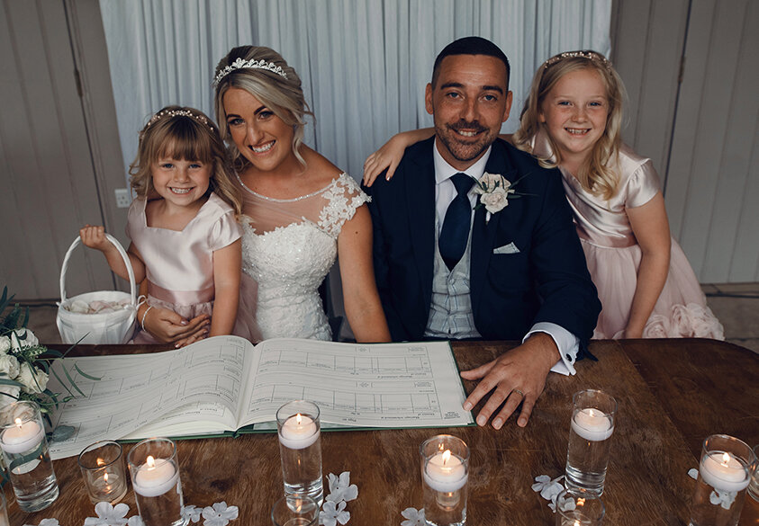 The bride and groom with the two children flower girls during the signing of the marriage register