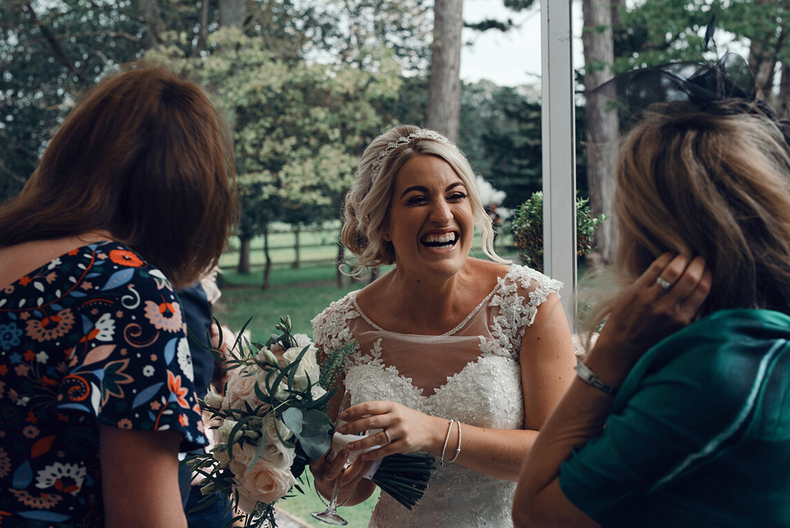 The bride laughing with two female wedding guests