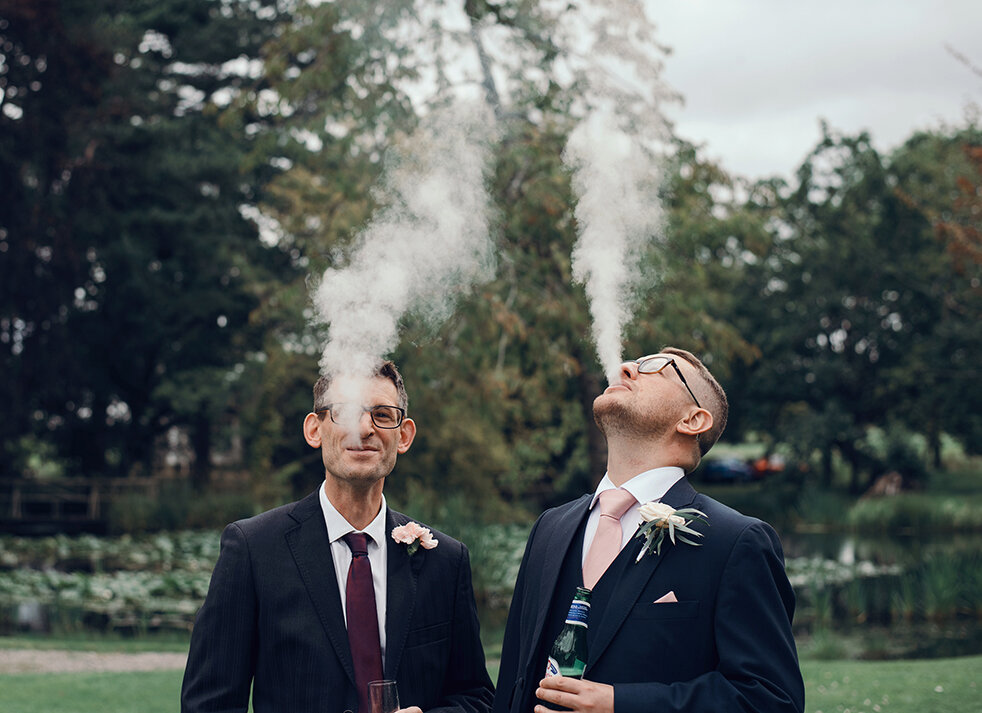 Two of the wedding guests blowing out from their vapes