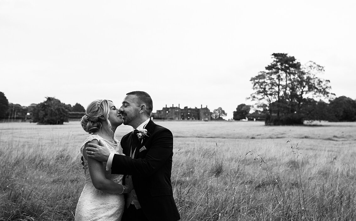 The bride and groom standing in a field kissing