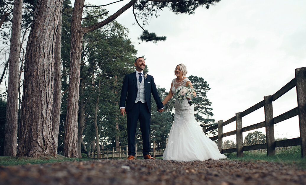 The bride and groom walking along a path in the woods