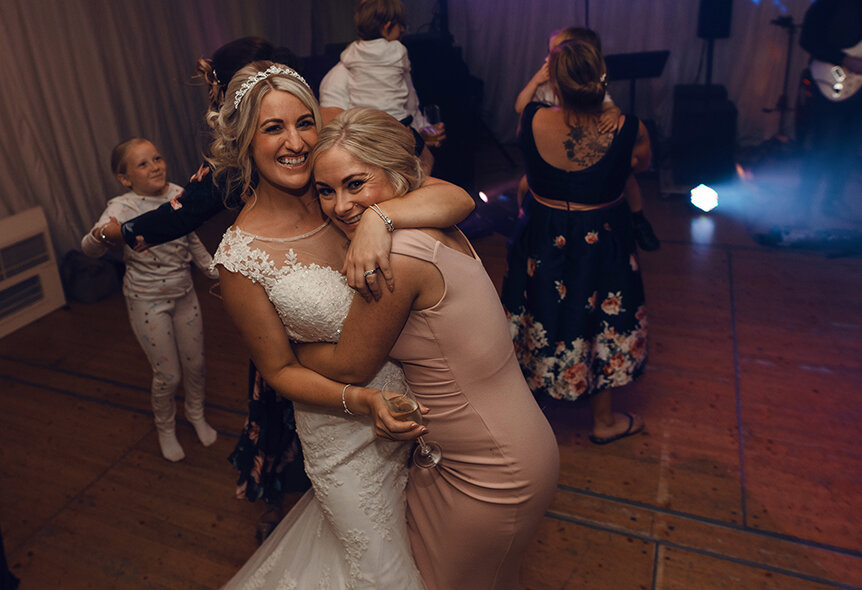 The bride and her best friend having a cuddle on the dance floor