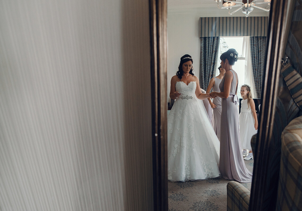The bride in her wedding dress reflected in a long mirror