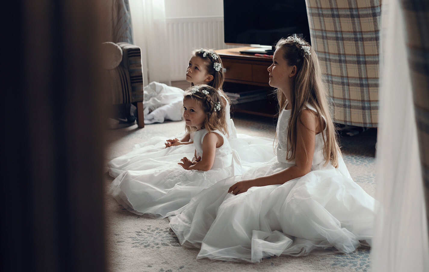 The three flower girls sitting on the floor admiring the wedding dress