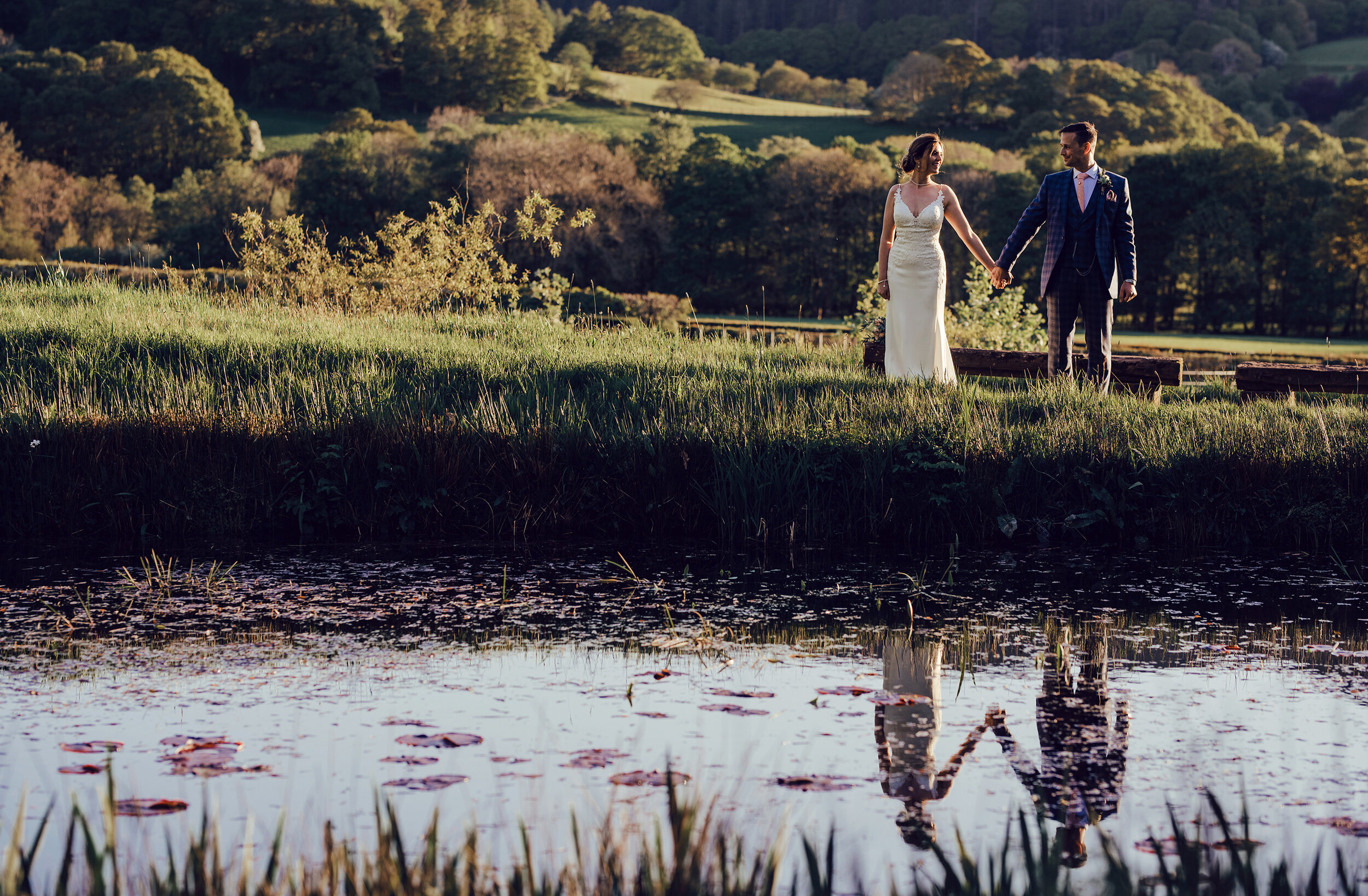 A bride and groom standing by the pool at New House Farm Cumbria