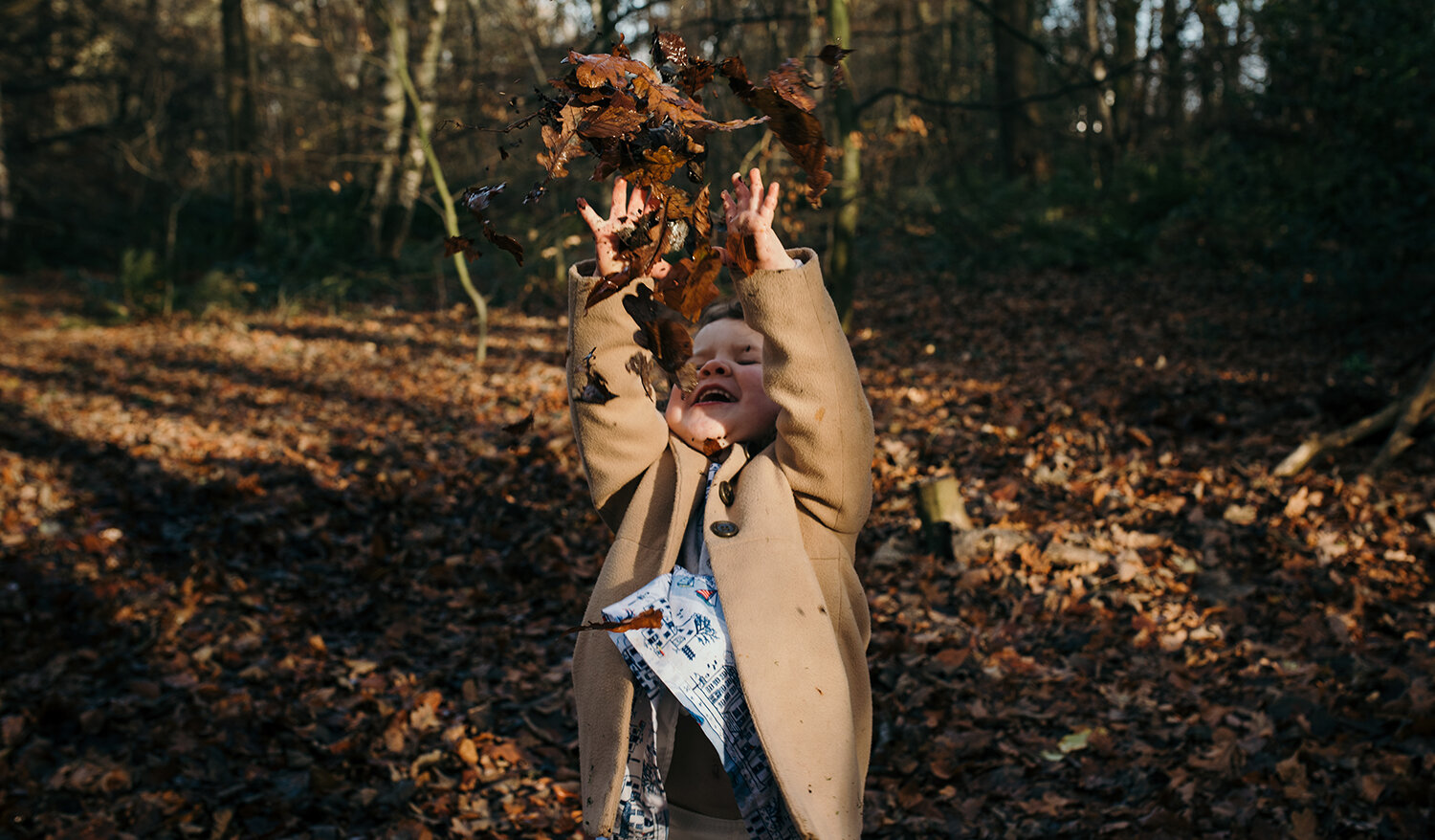 Little girl throwing dry leaves over her head