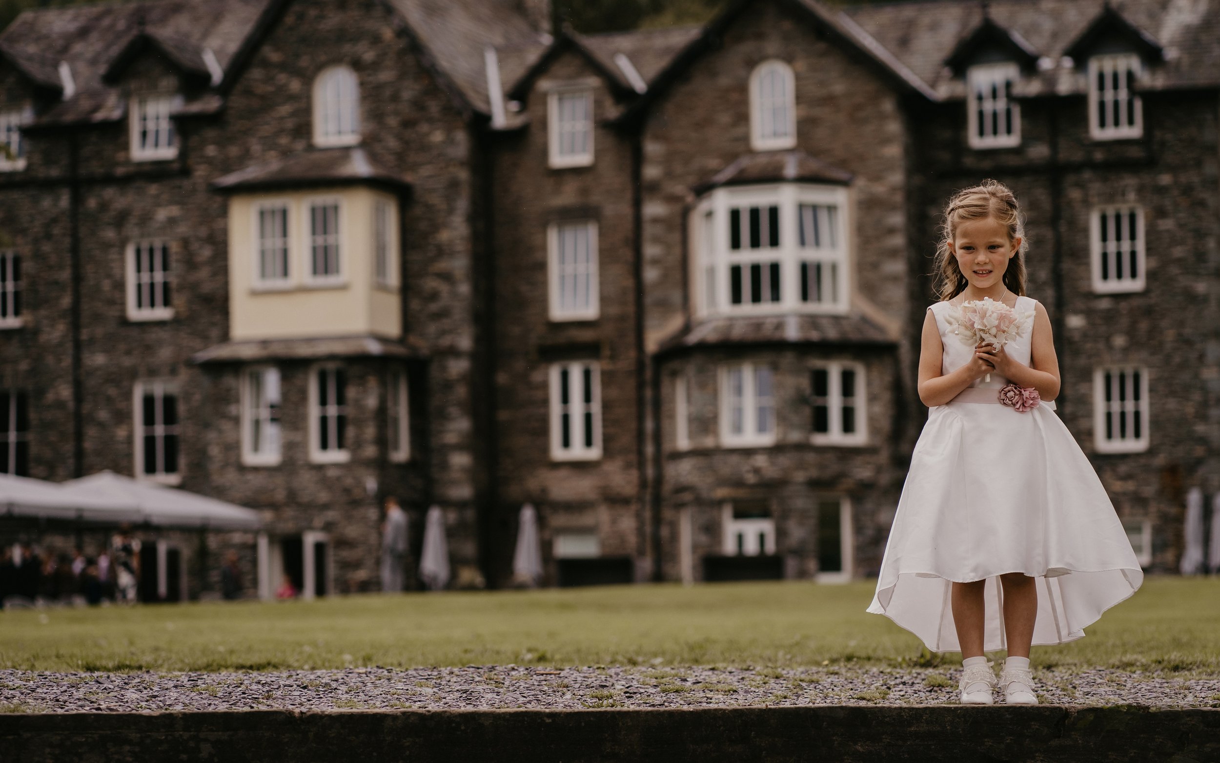 A flower girl standing in front of The Daffodil Hotel and spa Grassmere