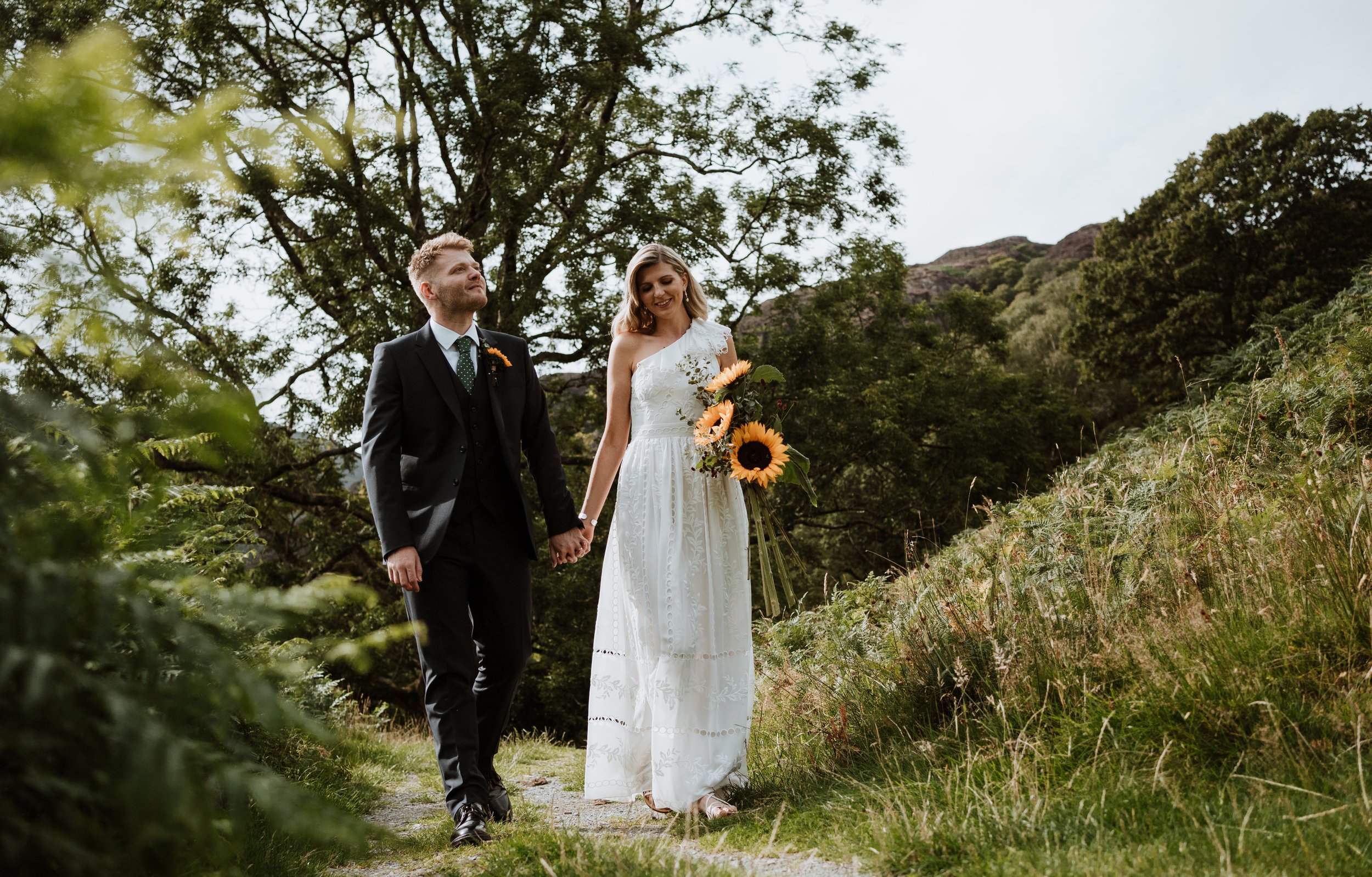Bride and groom walking along a path hand in hand