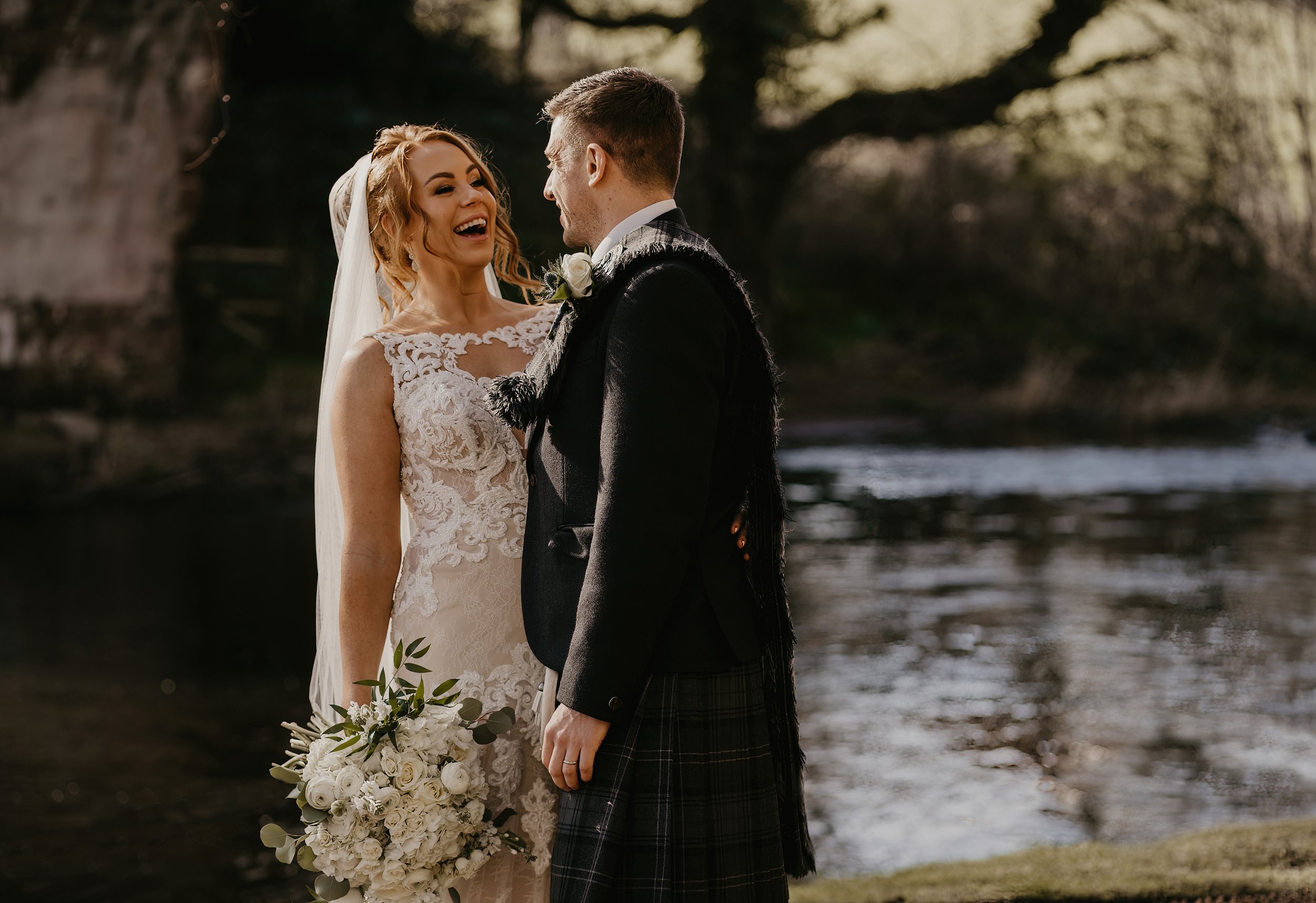 Bride and Groom standing at the rivers edge