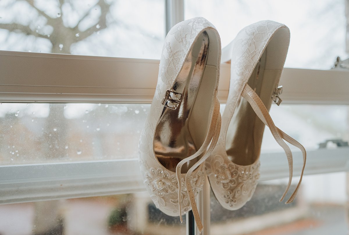The brides shoes hanging in the window