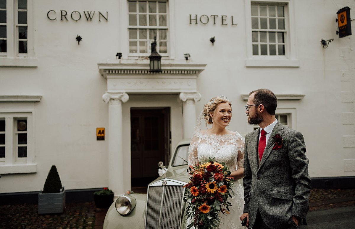 The bride and groom standing outside the hotel main entrance