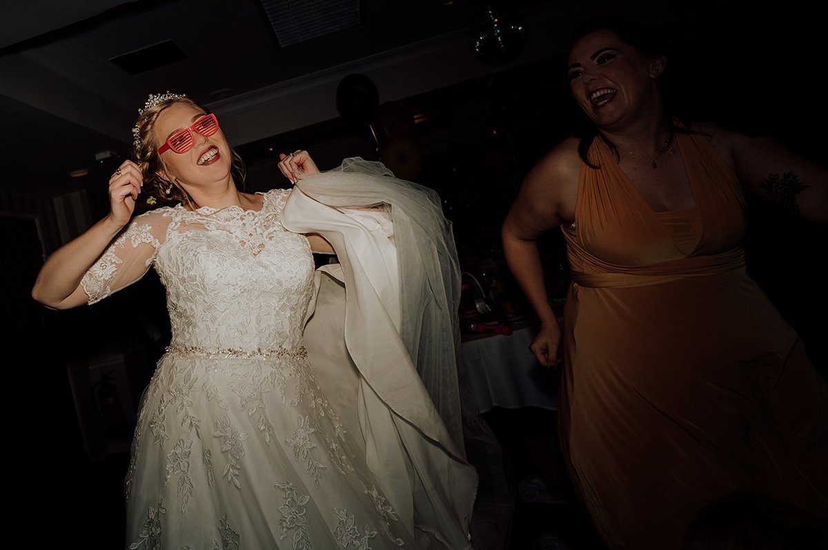 The bride on the dance floor wearing silly glasses