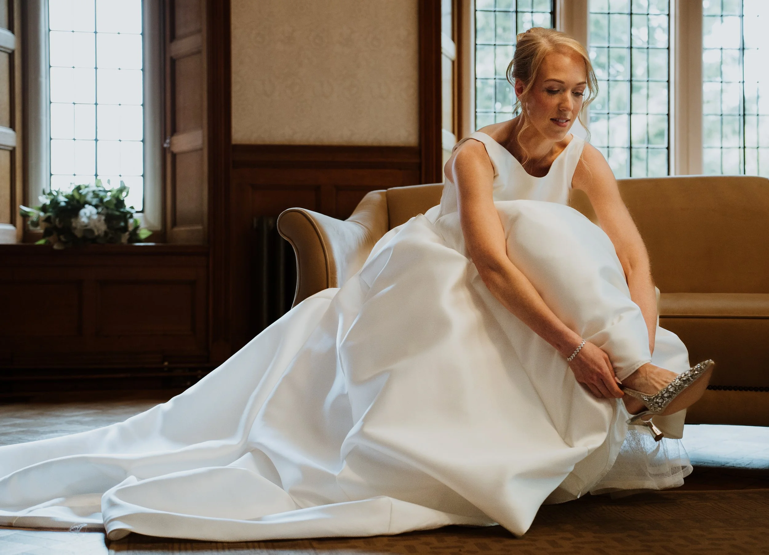 A bride sitting putting her shoes on