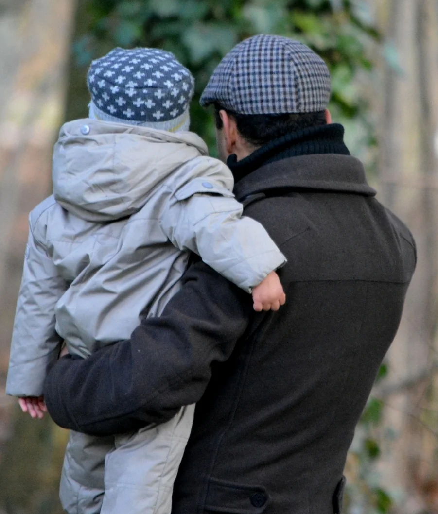 father holding baby looking at tree