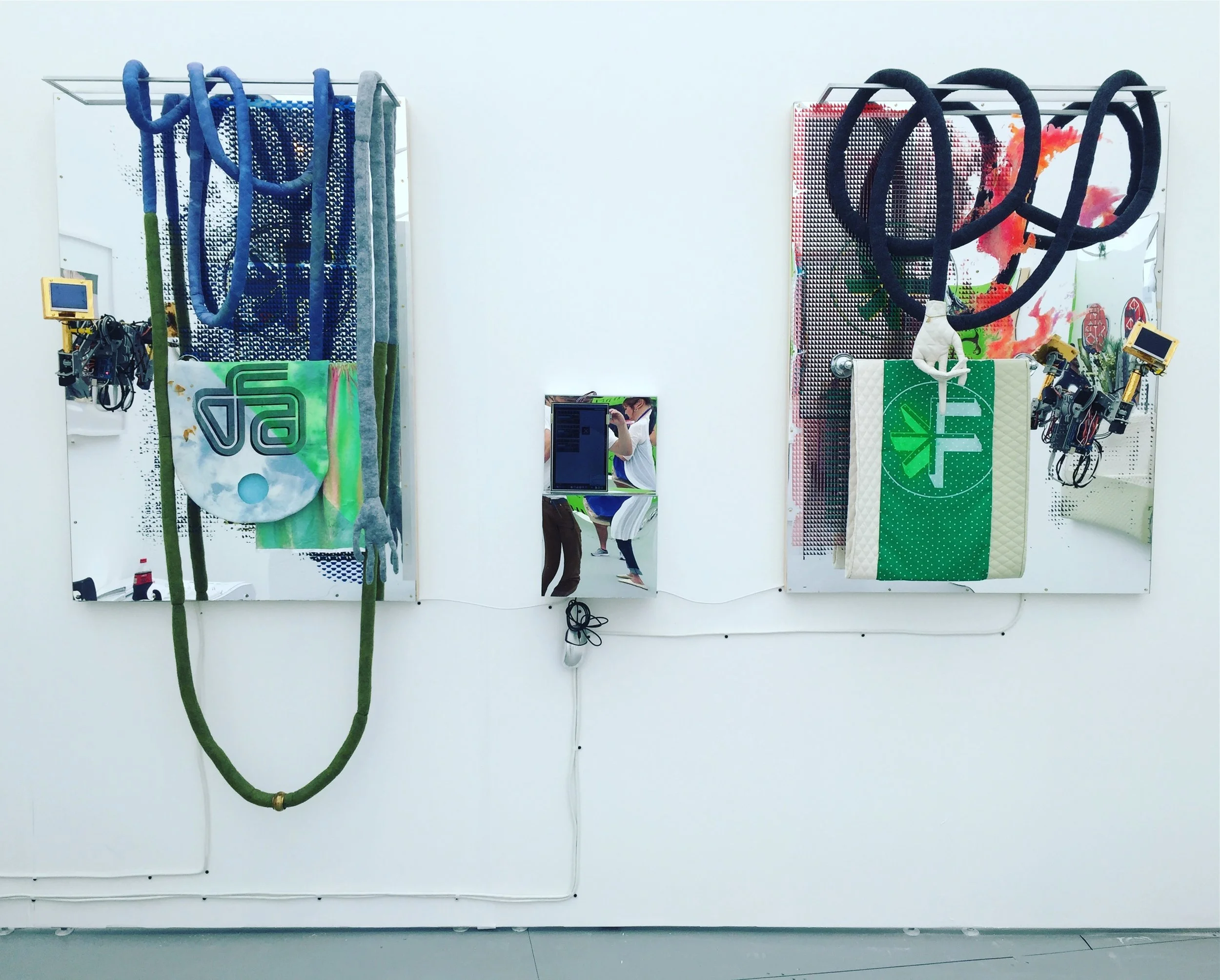 (L) Static Void: All You Need To Attract Click-Throughs , 2016, 50"x34.25", metal, fabric, ink, acrylic on mirror plexi, robotic arms, animations on monitors. (R) Host: You Need To Upload Two Different Versions , 2016, 49"x37", metal, fabric, ink, acrylic on mirror plexi, robotic arms, animations on monitors.