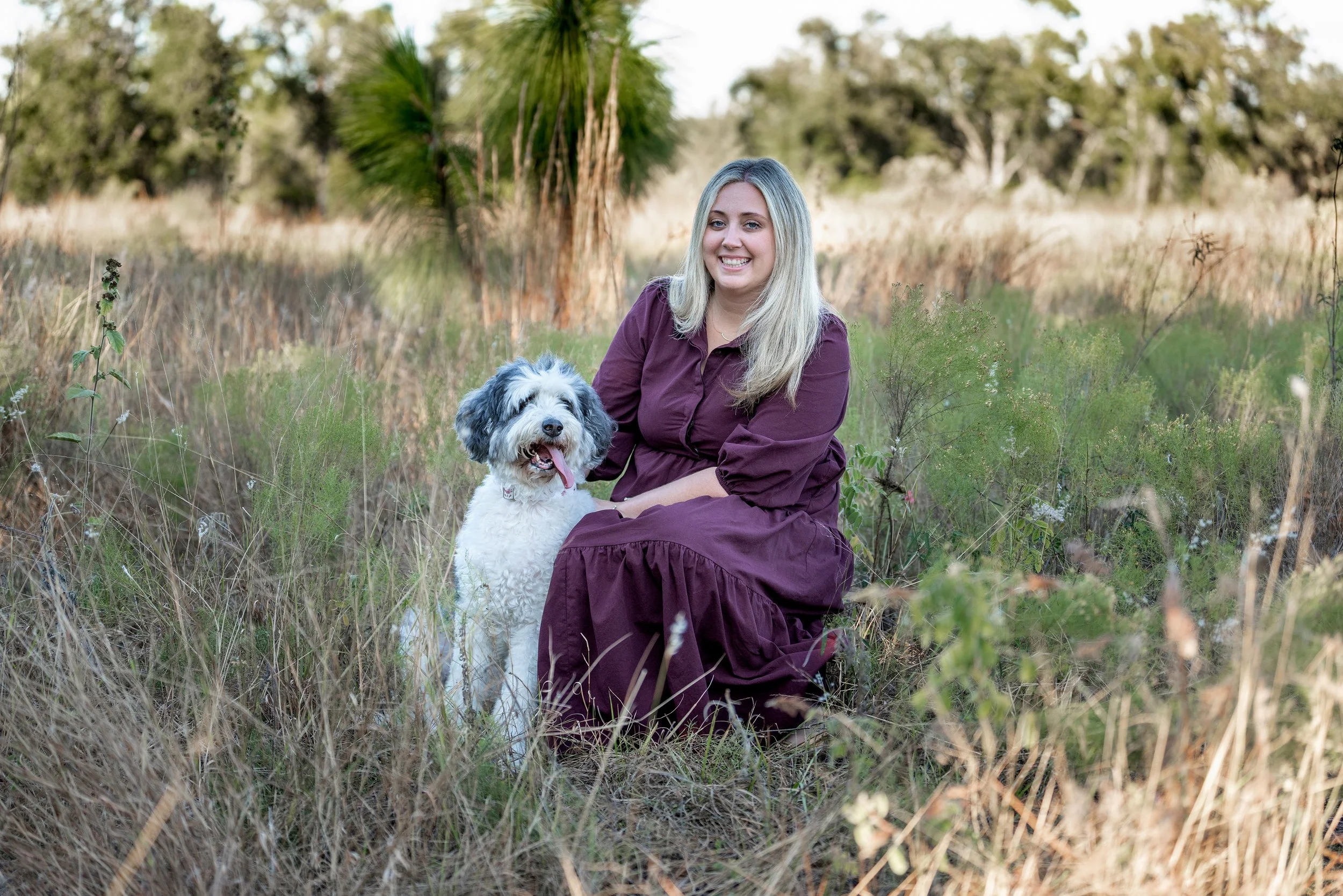 woman in florida field with her bernadoodle dog in fall