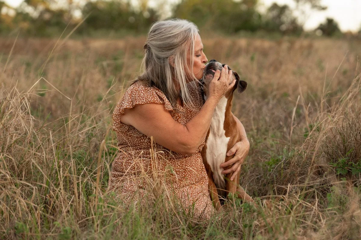 woman kissing her boxer dog in field in florida