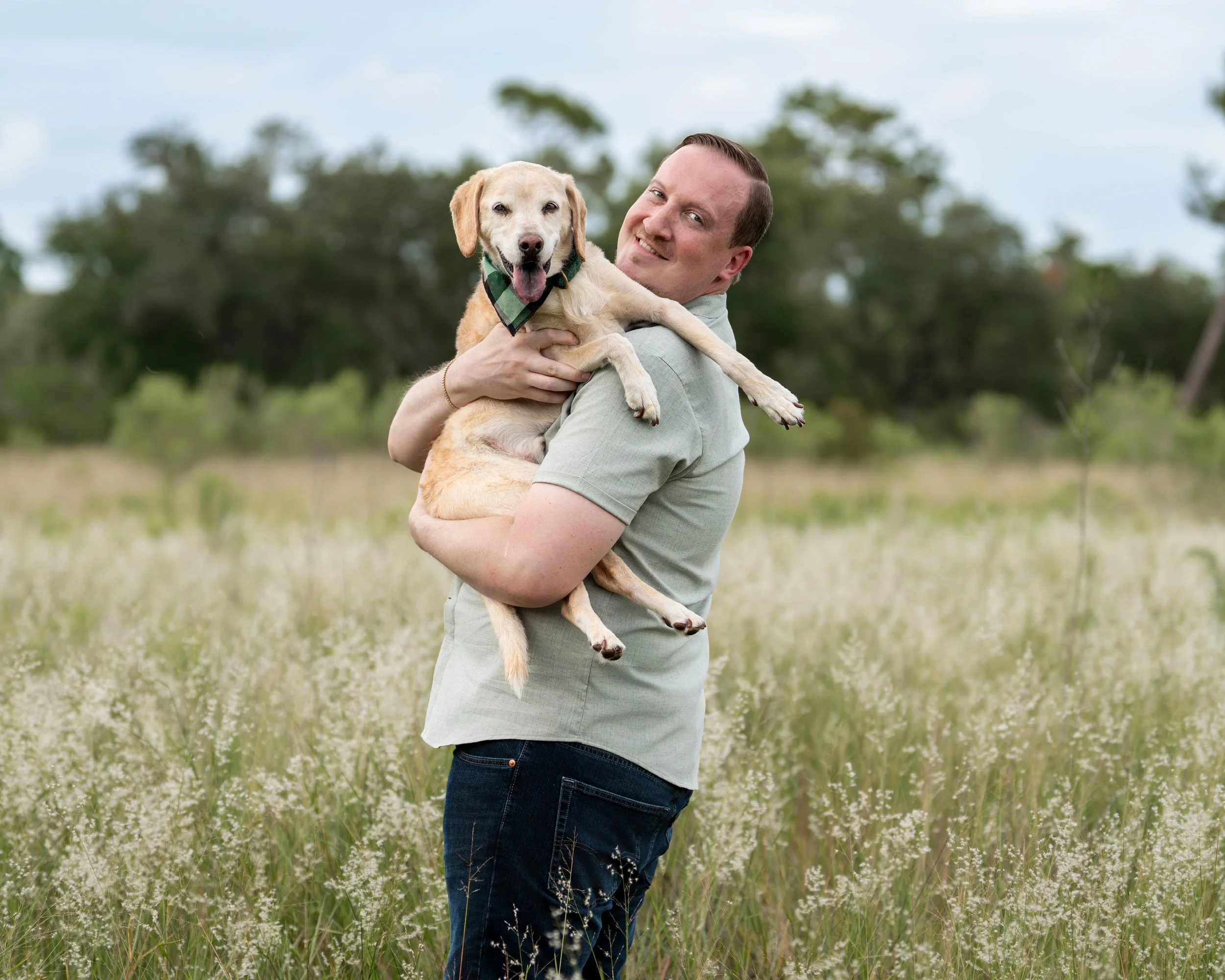 man holding his dog standing in a field in florida