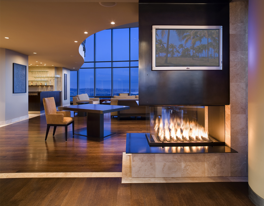 Seattle condo design showing custom steel and wood gas fireplace surround, hardwood floors, and great living room beyond