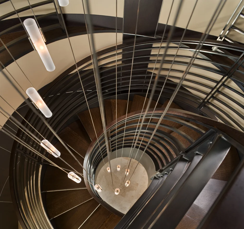 amazing spiral staircase with custom metal guardrail, stained wood treads, and spiral glass and steel chandelier