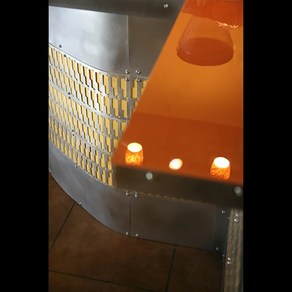 Coffee shop counter with orange back-painted glass and steel cabinet inlay