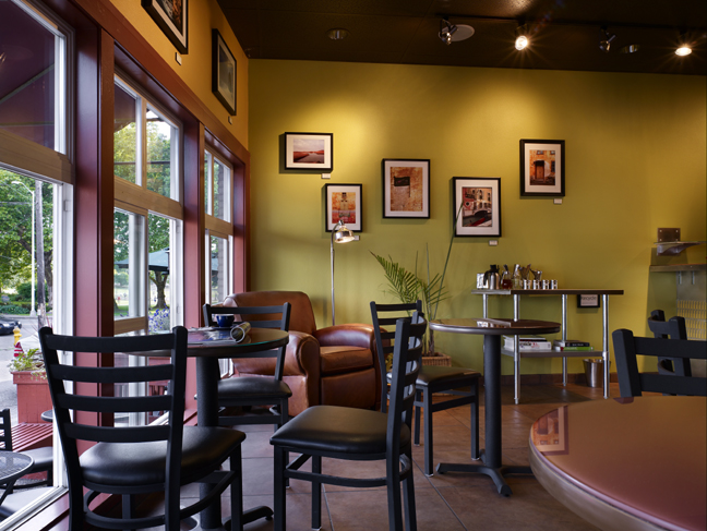 modern cafe seating with black leather chairs and back-painted glass table tops with a great leather seat and floor lamp beyond