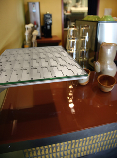 Cafe 'pick-up' shelf with custom metal top and back painted glass with custom teapot beyond