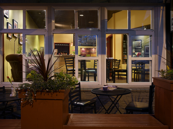 cafe exterior sidewalk seating with black table and chairs, planters and benches for community seating