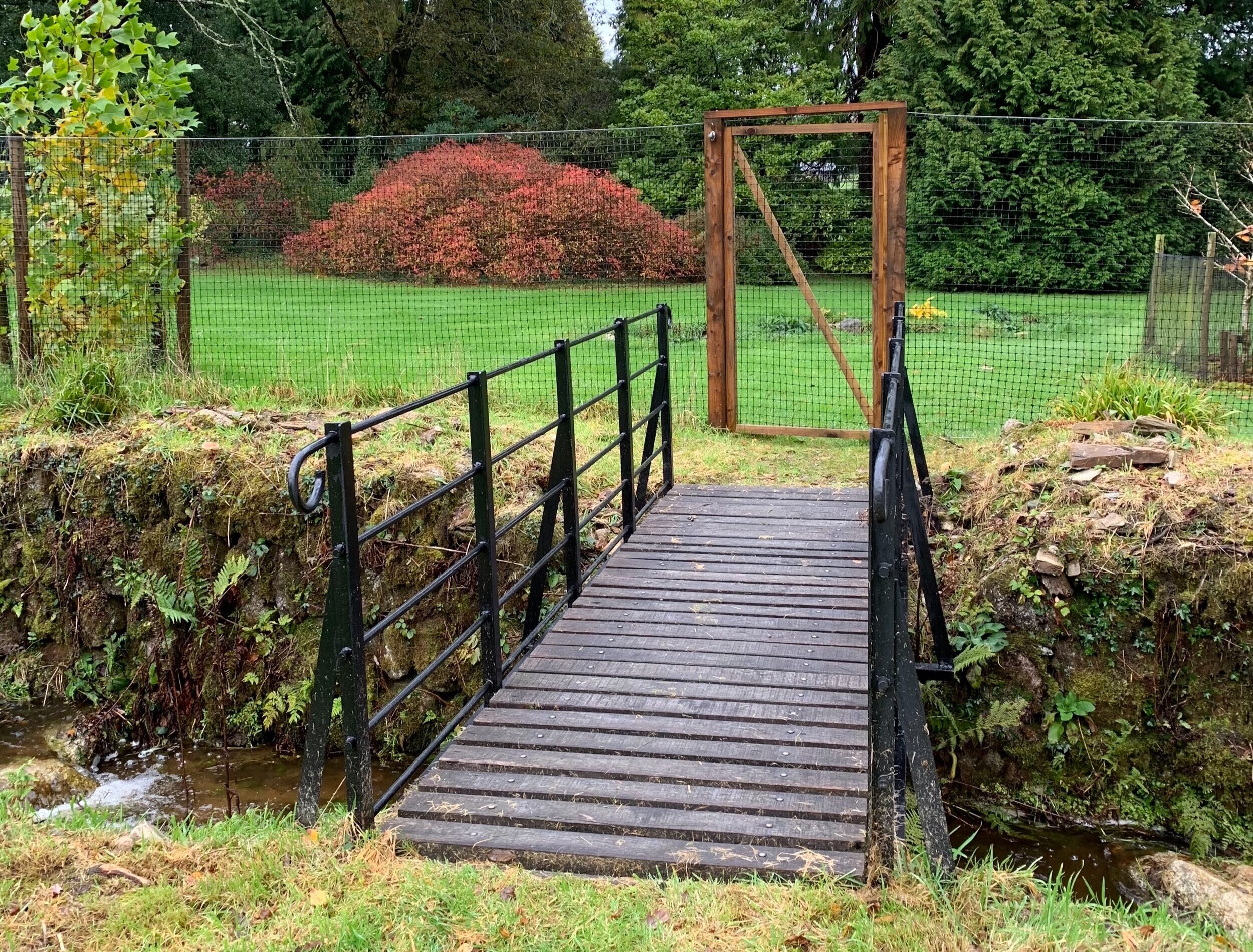 Footbridge in memory of Roger Latham and deer fence beyond