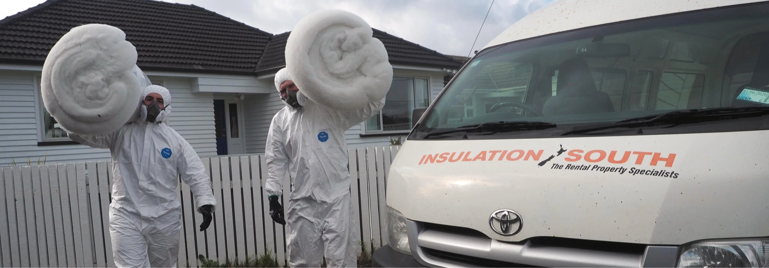 Insulation South carrying bales of insulation to install into a house.