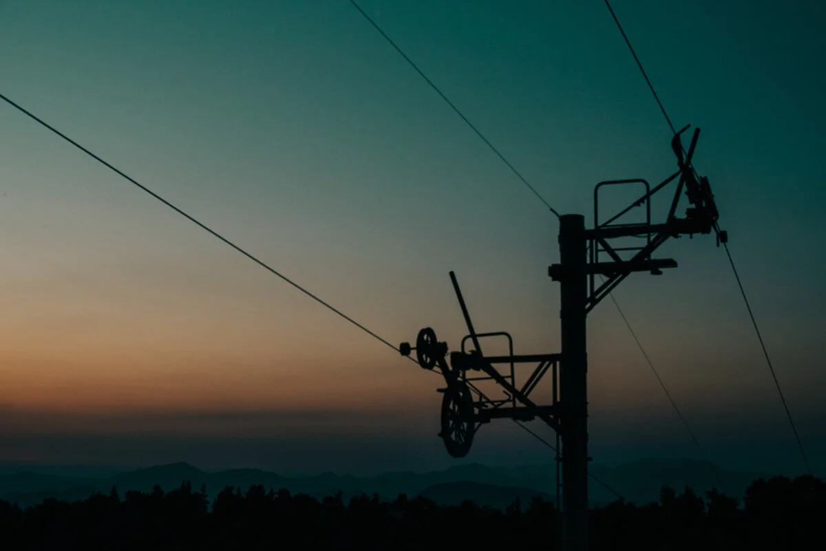 silhouetted top of ski lift against blue and orange sky at sunset mont serein