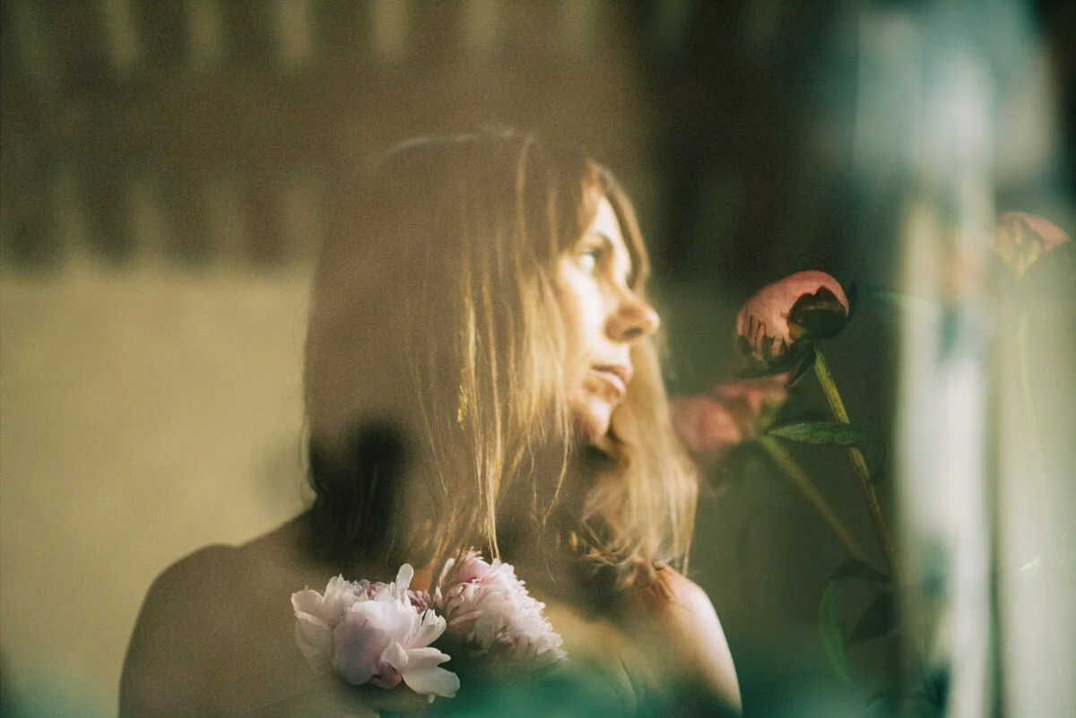 brown haired woman looking right with overlap of pink flowers