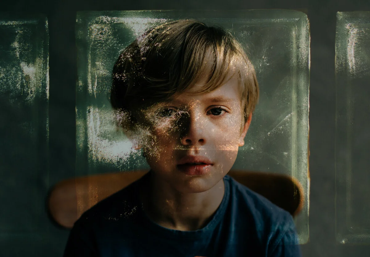 blond haired boy looking sad  in blue top with overlap of texture
