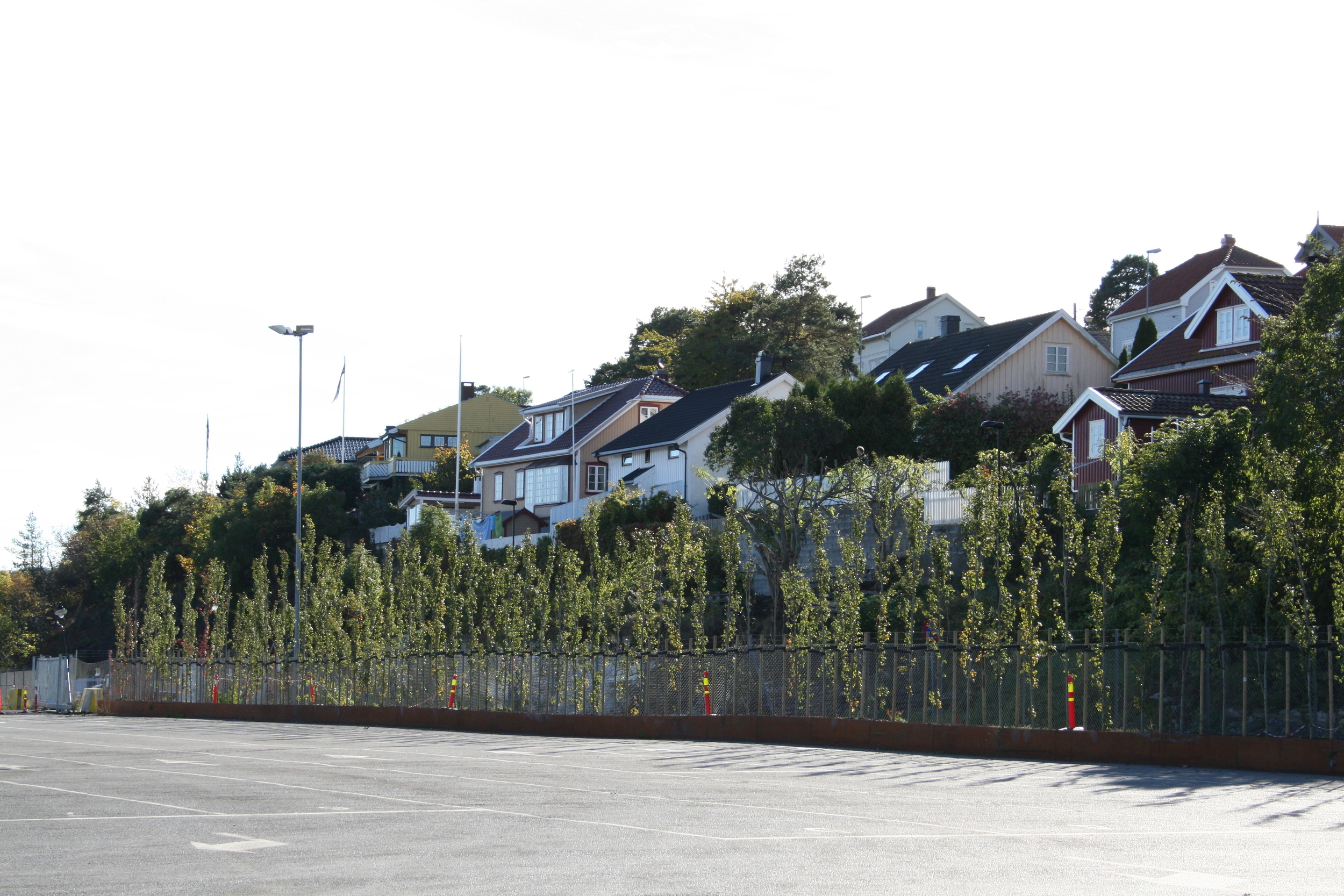   Ei 80 meter lang plantekasse av skipstål gir rom for en tett planting av søyleosp, som danner skjerming mellom boligene på knausene og de store flatene i havneområdet  
