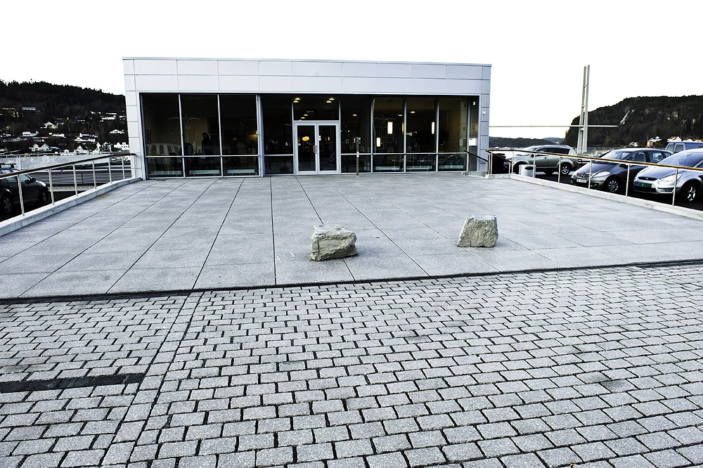   Byggets inngangsparti med granittheller på plassen. Grenlandsbrua i bakgrunnen. Foto: Dag Jenssen  