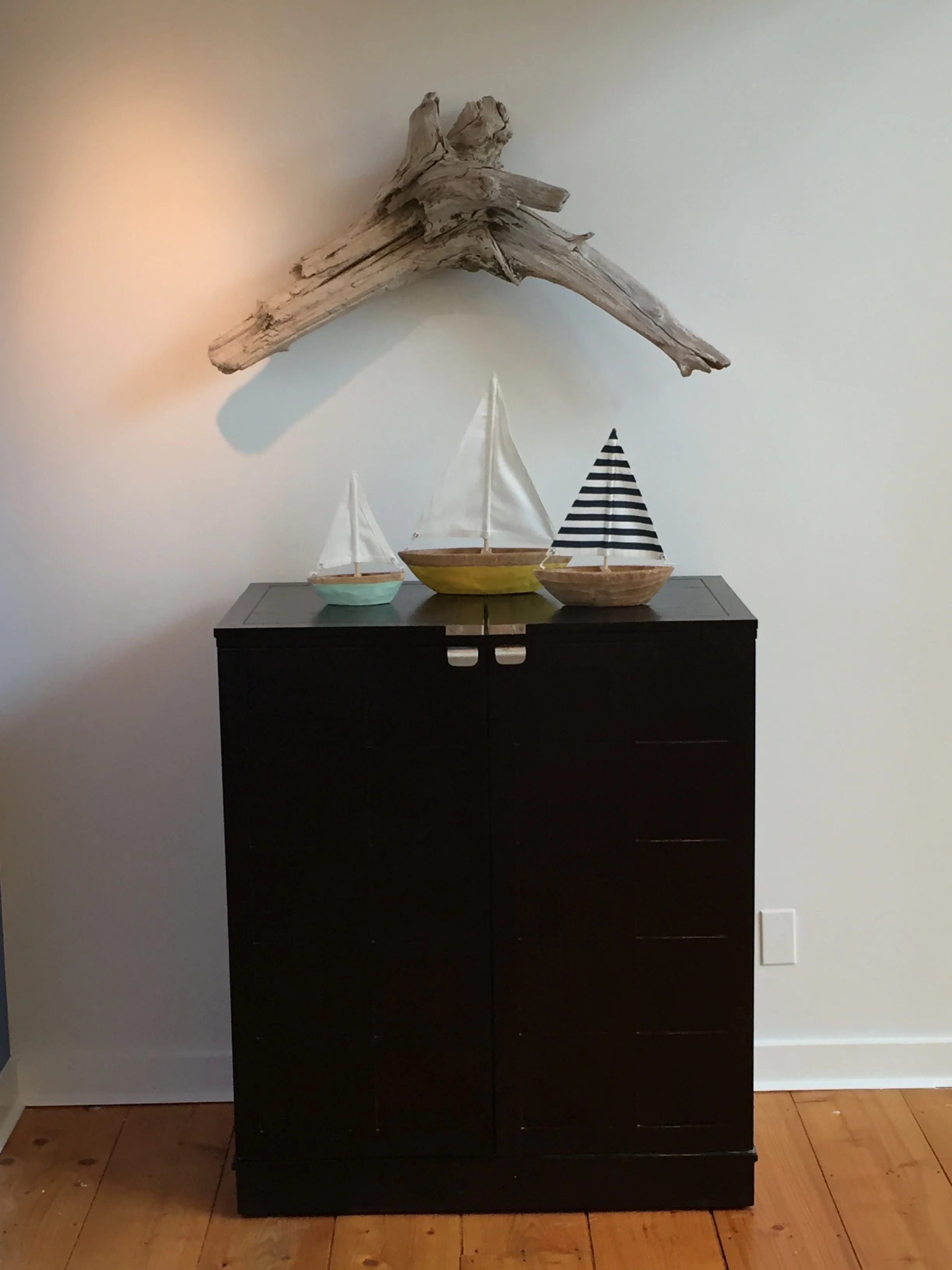 The homeowner's existing bar cabinet is softened by using a unique piece of driftwood that they found as artwork. It is the perfect personal touch for the space.