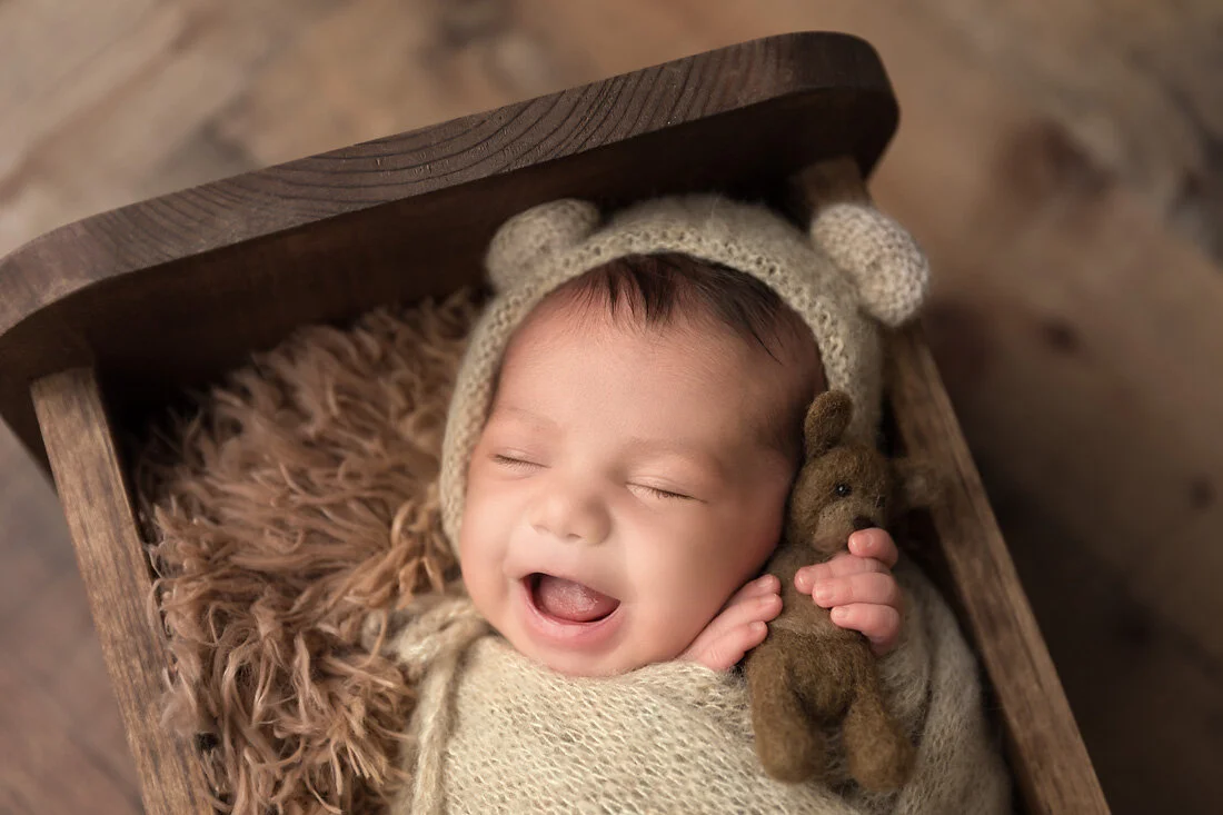 newborn boy with teddy bear and big smile