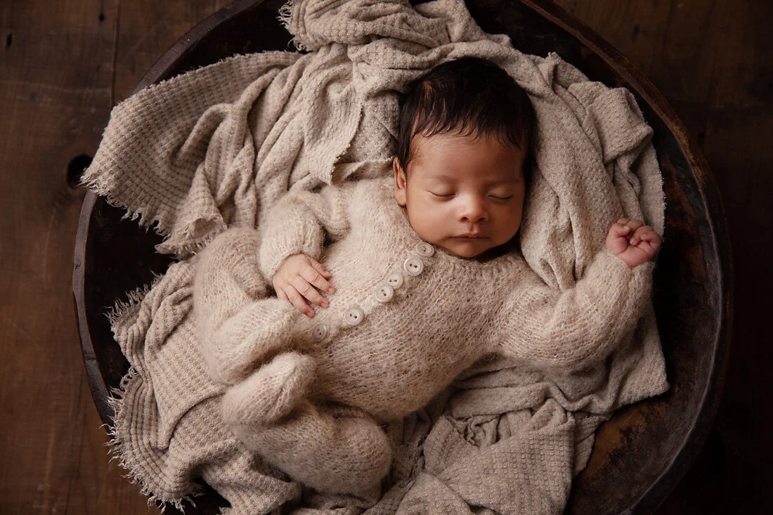 newborn boy in bowl prop with beige layer