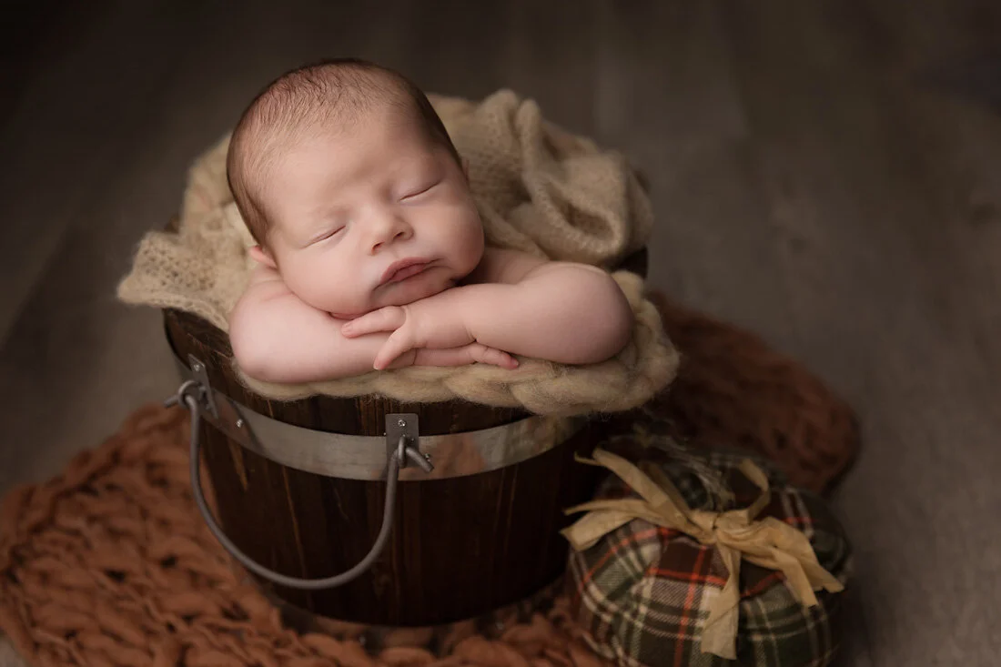 newborn boy in bucket prop with fall decorations