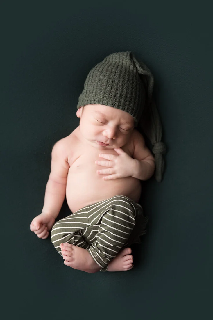 newborn boy in green pants and hat