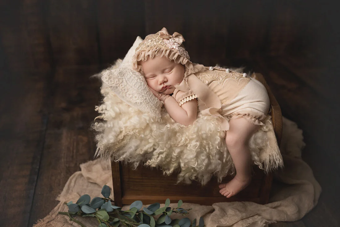 newborn sleeping on curly wool and bed prop