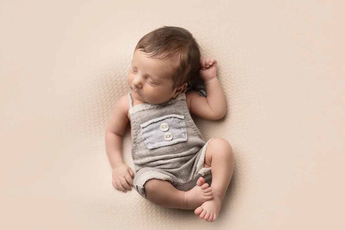 newborn boy in gray overalls