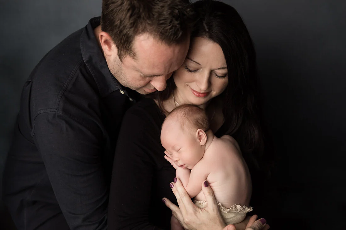 parents cuddling newborn boy