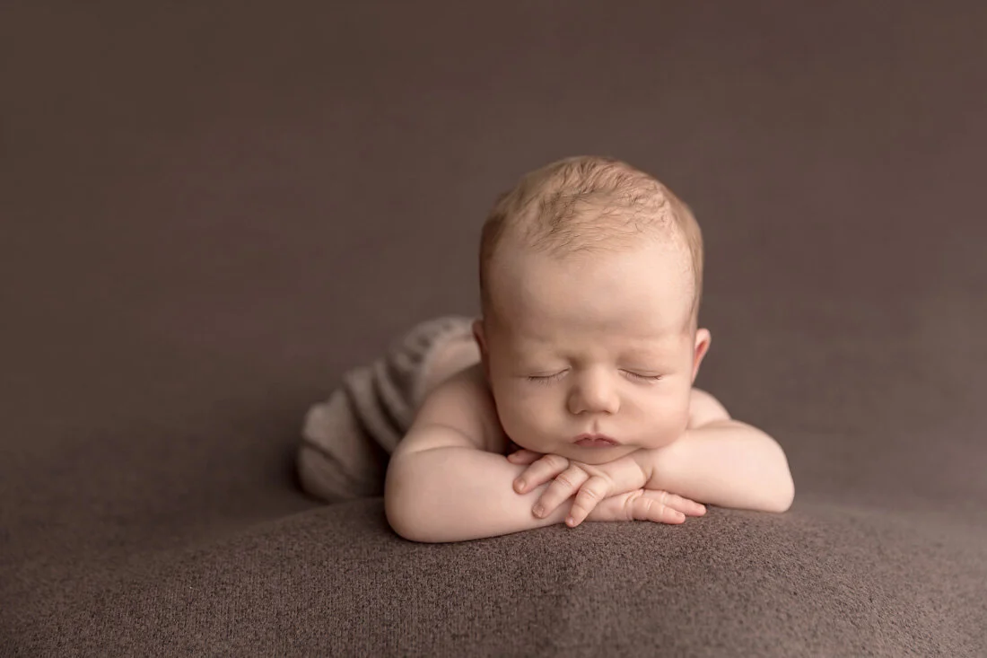 head on hands newborn pose on brown