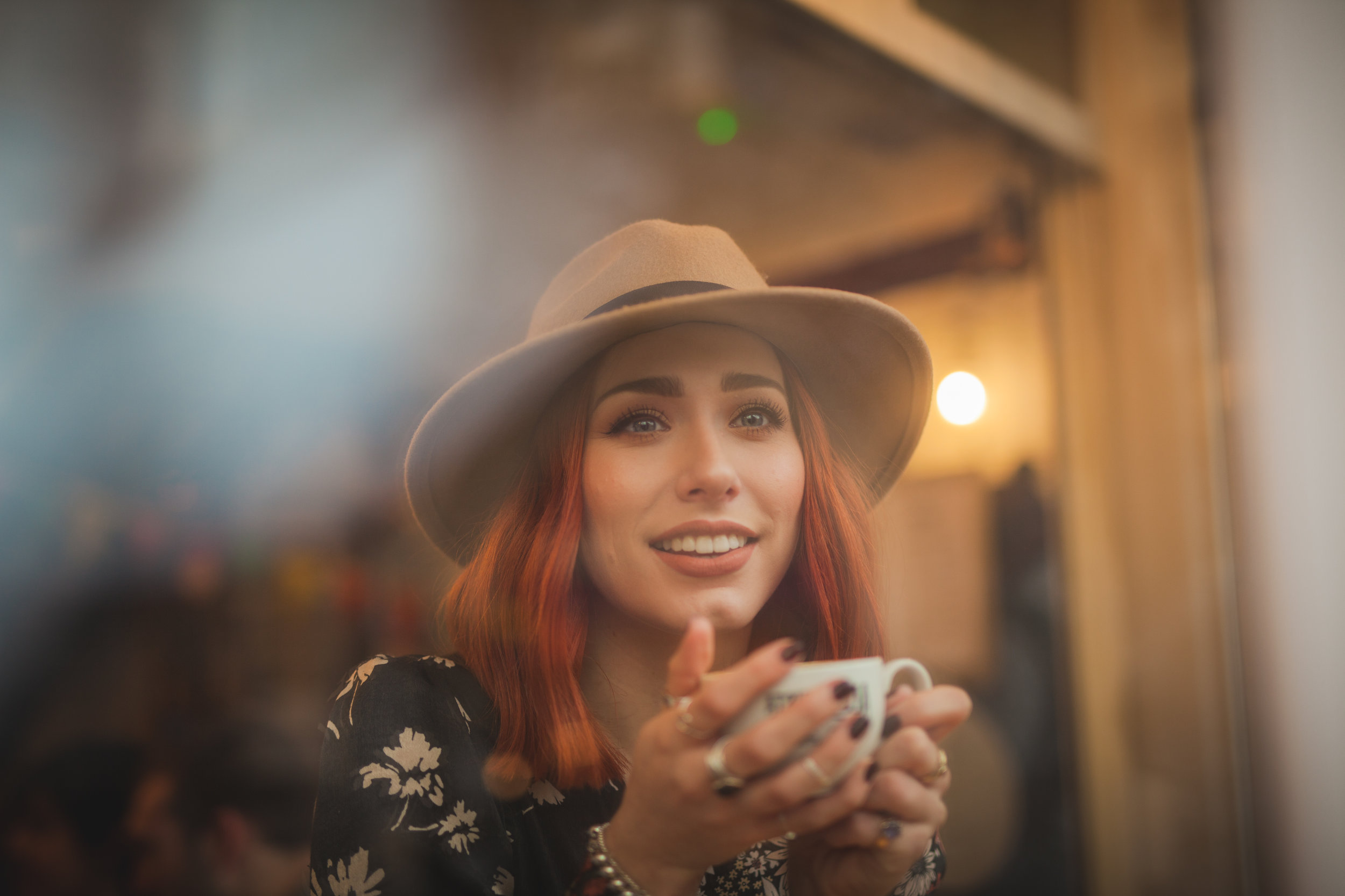 Red head model poses for a photoshoot looking through a window holding a coffee