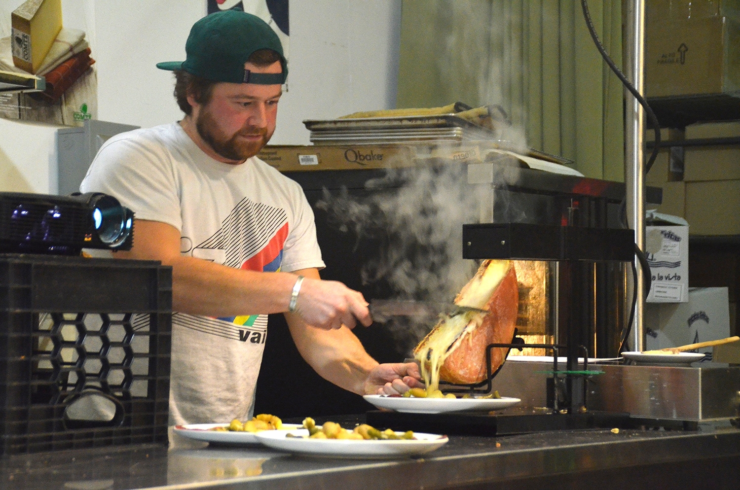 Tripp scrapes a layer of melted cheese on top of the potatoes to make a plate of raclette