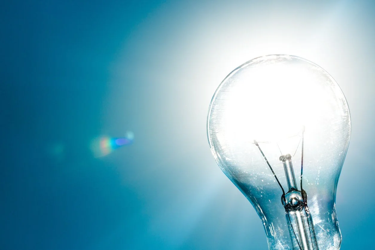 Close-up of a glowing incandescent light bulb against a blue background