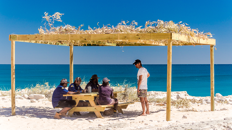 Tourist Shane admires a bough shed built by the rangers. The rangers have been building bough sheds at community beaches to facilitate a more enjoyable experience for tourists, and their fellow community members.