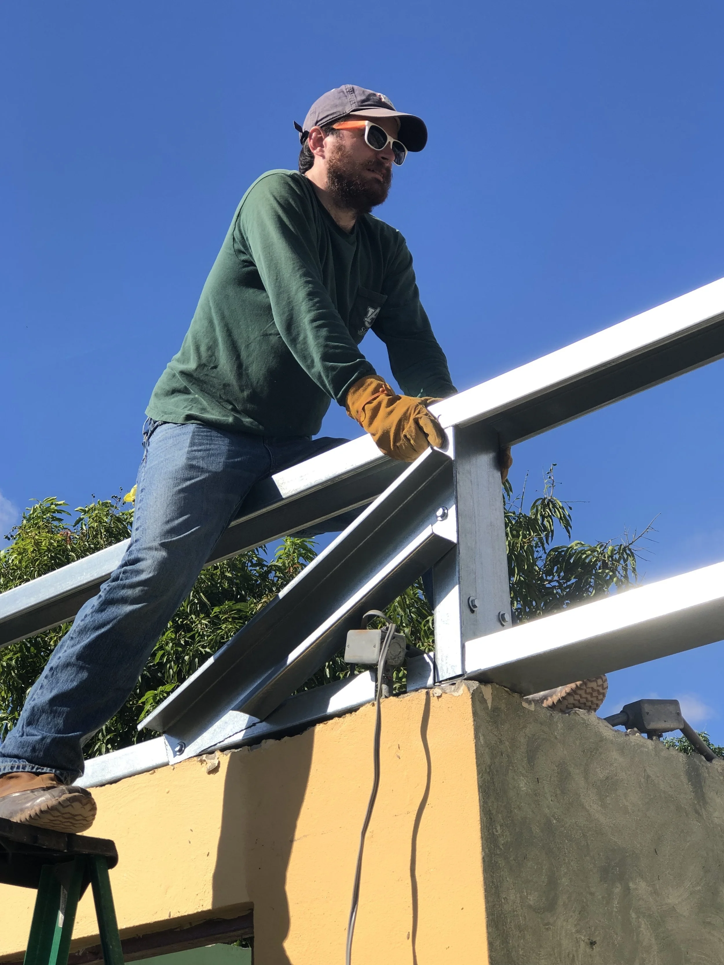 JT Mercer from Team 1 is shown here braving the highest part of a roof on the second story to hold down the support beams for what will be a new metal roof.