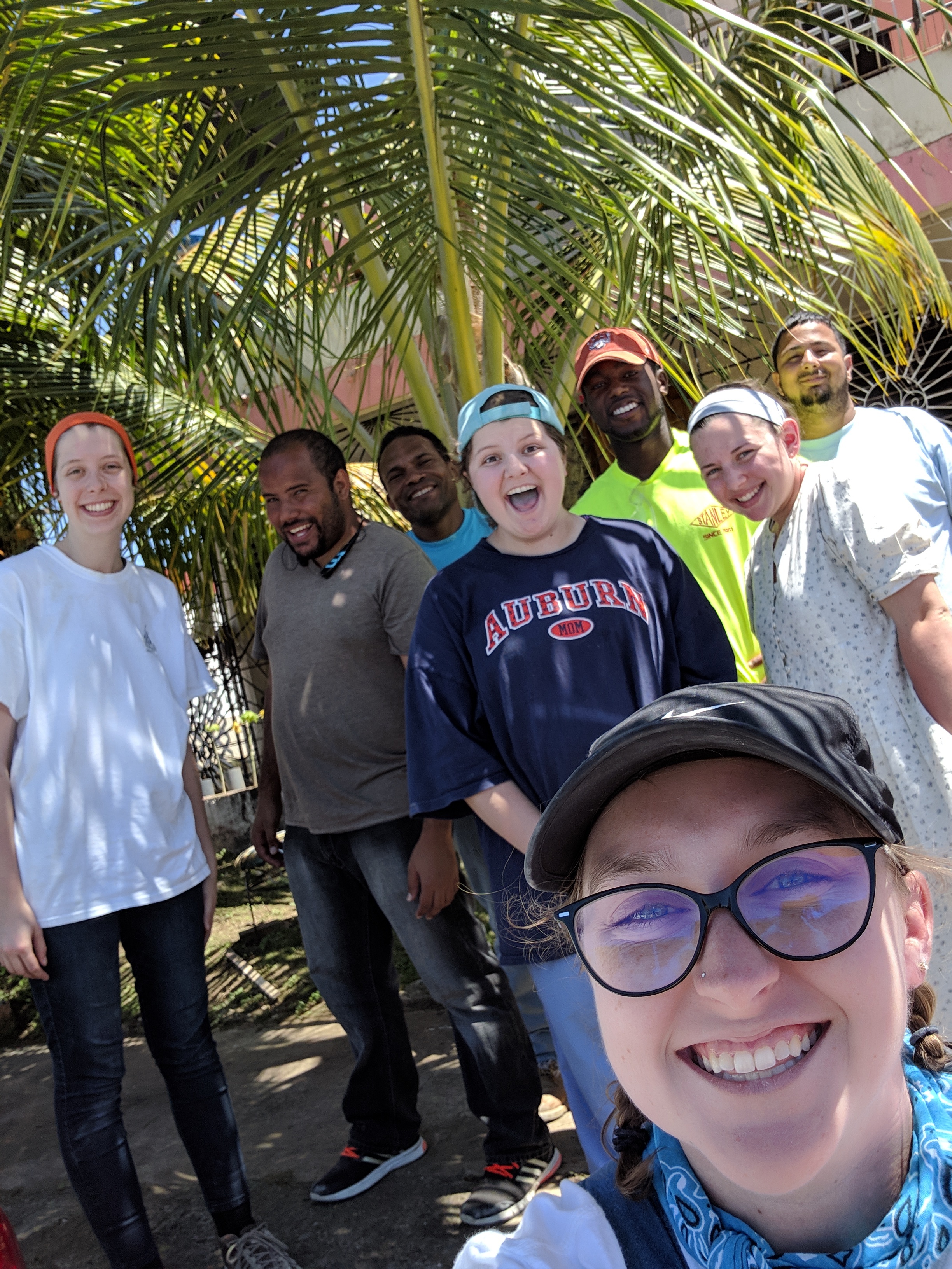 An excited Team 2/ Agua de Coco smiles under a palm tree as they finish up the week’s work